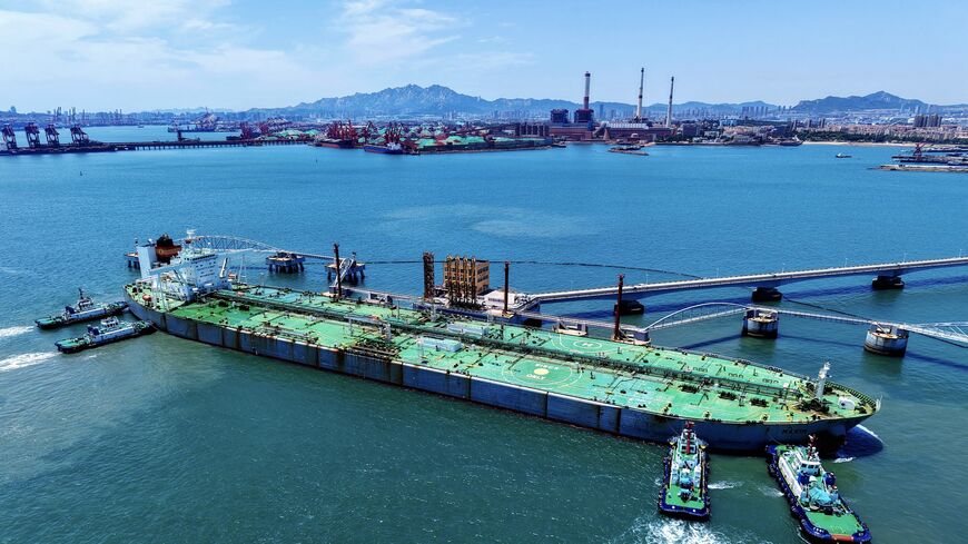 A ship loaded with oil docks at a pier with the help of a tugboat at the port of Qingdao, in eastern China's Shandong province, on June 12, 2025.