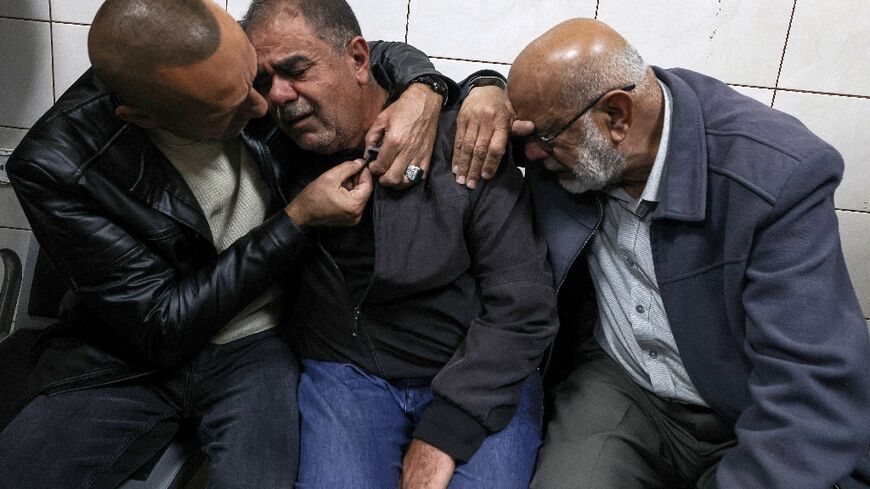 Palestinians try to console the father of Bahaa Abdel-Rahman Rashid at the nearby city of Nablus' Rafidia hospital