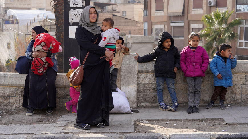 A woman carries her child as she flees, following renewed clashes between the Syrian army and the Syrian Democratic Forces (SDF), in Aleppo, Syria, January 7, 2026. REUTERS/Karam al-Masri