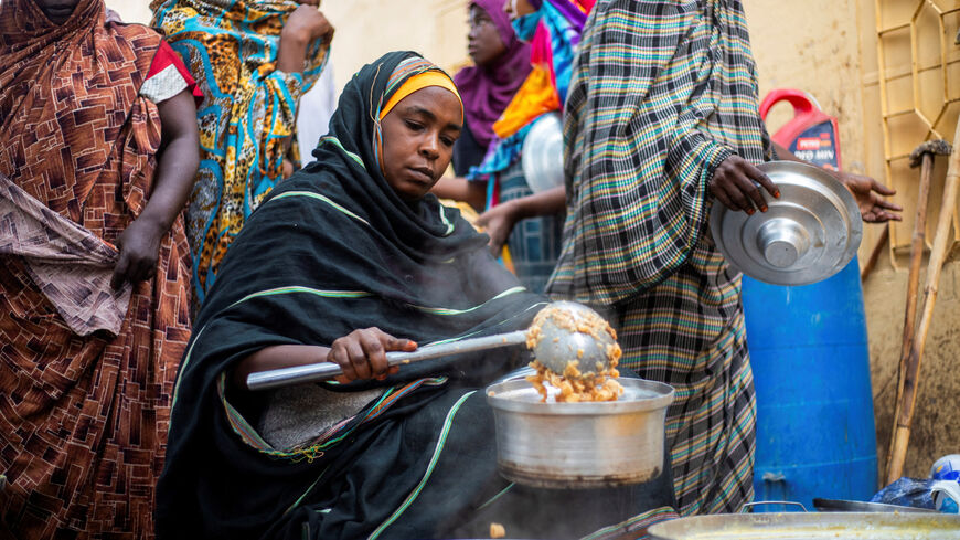 FILE PHOTO: A Sudanese woman from a community kitchen run by local volunteers distributes meals for people who are affected by conflict and extreme hunger and are out of reach of international aid efforts, in Omdurman, Sudan, August 22, 2024. REUTERS/Mazin Alrasheed/File Photo