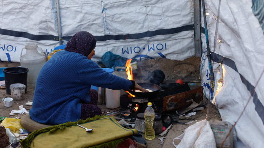 A woman cooks as displaced Palestinians shelter in a tent camp in Deir al-Balah, central Gaza Strip, January 19, 2026. REUTERS/Mahmoud Issa
