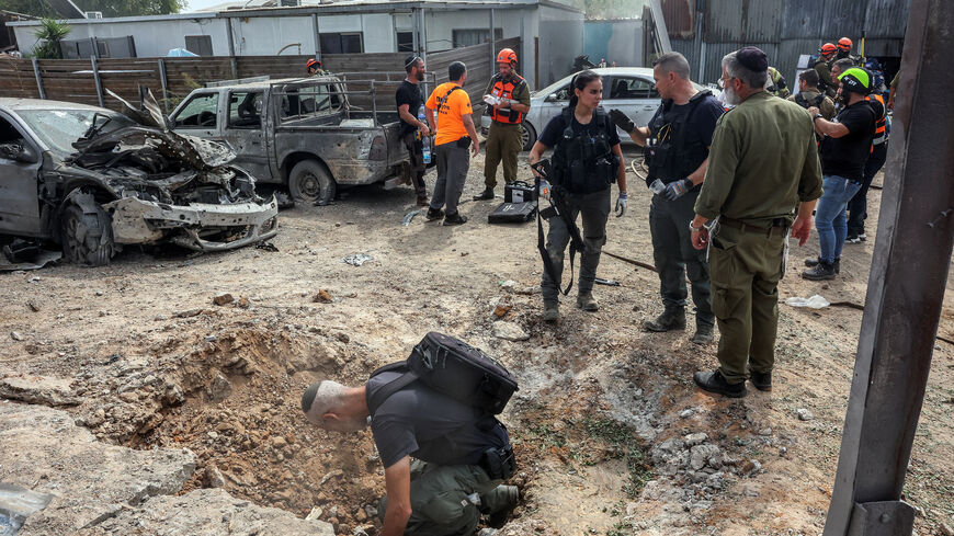 A security official investigates the crater formed when a projectile landed, after Hamas' armed wing said it attacked Tel Aviv with a missile salvo, amid the ongoing Israel-Hamas conflict, in Kfar Chabad, Israel, October 7, 2024. REUTERS/Itai Ron/File Photo