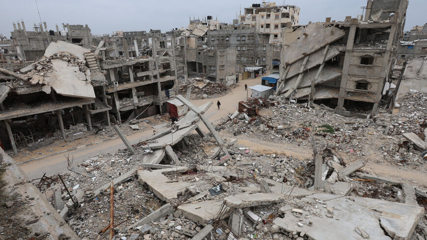 Palestinians walk surrounded by the rubble of houses destroyed in Israeli strikes during the war, in Khan Younis, southern Gaza Strip, January 22, 2026. REUTERS/Ramadan Abed
