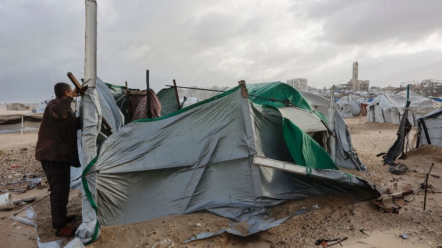 A displaced Palestinian fixes a tent in Gaza City