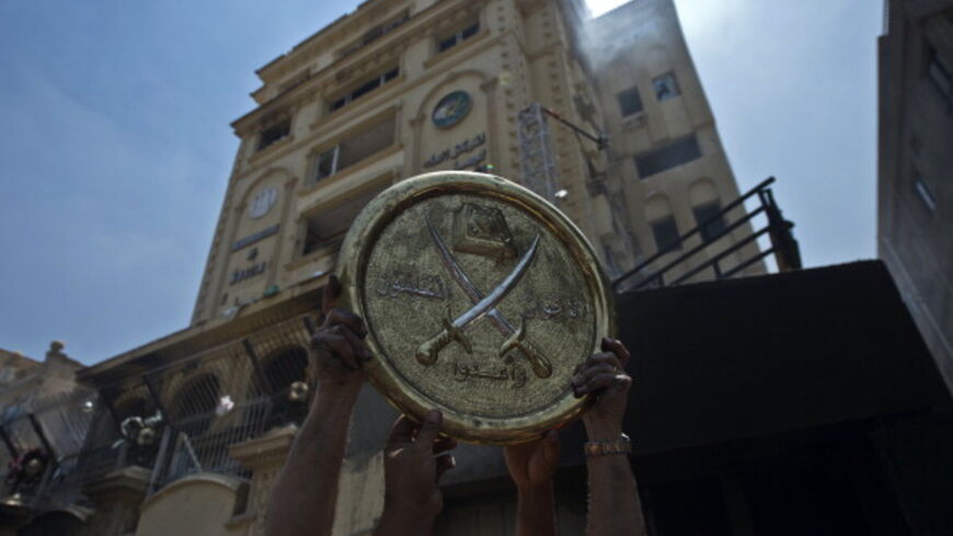 Egyptians hold a plaque of the Muslim Brotherhood emblem which was removed from the party's burnt headquarters in the Moqattam district of Cairo on July 1, 2013 after it was set ablaze by opposition demonstrators overnight. Egypt's opposition gave Islamist Mohamed Morsi a day to quit or face civil disobedience after deadly protests demanded the country's first democratically elected president step down after just a year in office. AFP PHOTO / KHALED DESOUKI (Photo credit should read KHALED DESOUKI/AFP via G