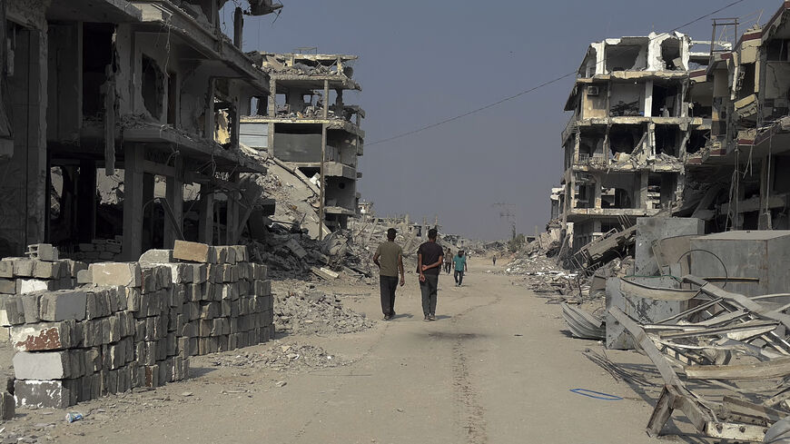 Men pass by the destroyed Haifa Bakery in Khan Yunis, Gaza Strip, on Nov. 6, 2025. 