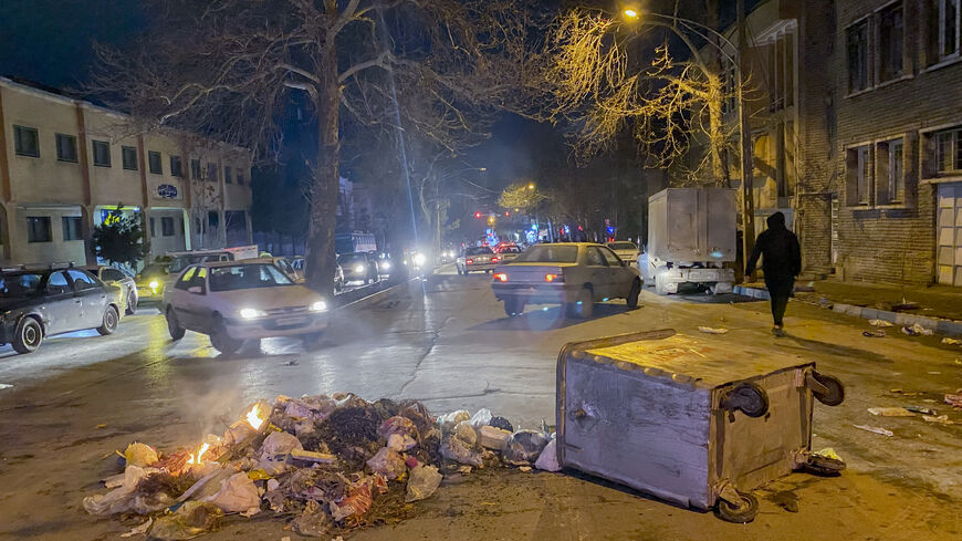 Burning debris lies next to an overturned dumpster in the middle of a street during unrest amid demonstrations in Hamedan, Iran, on January 1, 2026. The demonstrations erupted after shopkeepers in Tehran's Grand Bazaar shut their businesses to protest the sharp fall of Iran's currency and worsening economic conditions, with clashes reported in several provinces and Iranian media and rights groups saying multiple people were killed in the violence, marking the largest protests to hit the Islamic Republic in 