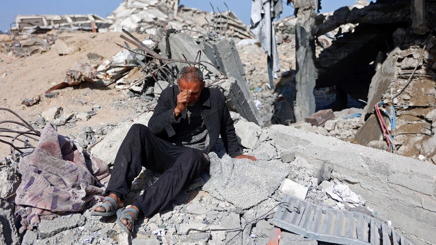 A man sits in the rubble of Sheikh Radwan police station in Gaza City after the Israeli air strike