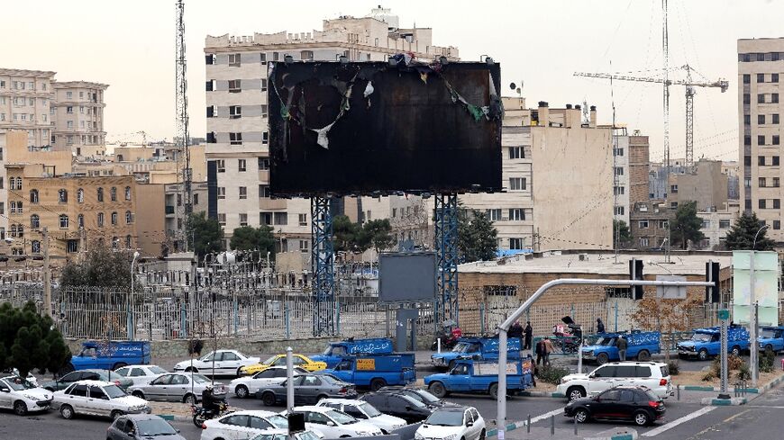 Vehicles drive past a burnt billboard as daily life returned to the streets of Iran's capital following nationwide protests