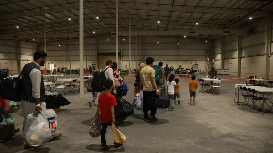 Special Immigrants from Afghanistan walk through the in-processing building after their evacuation at Camp As Sayliyah, Qatar, August 20, 2021. Picture taken August 20, 2021.  U.S. Army/Sgt. Jimmie Baker/Handout via REUTERS