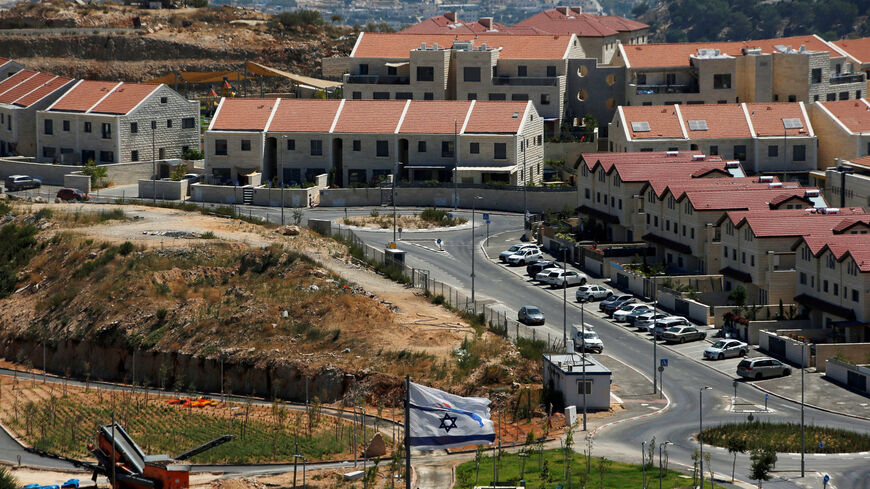 FILE PHOTO: The Israeli national flag flutters as apartments are seen in the background in the Israeli settlement of Efrat in the Israeli-occupied West Bank August 18, 2020. REUTERS/Ronen Zvulun/File Photo