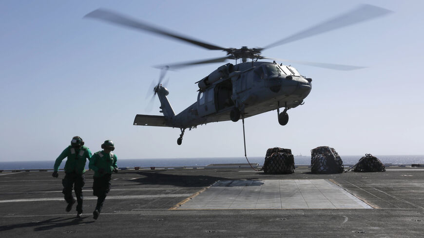 In this handout photo provided by the US Navy, Logistics Specialist 1st Class Ousseinou Kaba (left), from Silver Spring, Md., and Logistics Specialist Seaman Abigail Marshke, from Flint, Mich., attach cargo to an MH-60S Sea Hawk helicopter from the "Nightdippers" of Helicopter Sea Combat Squadron (HSC) 5 from the flight deck of the Nimitz-class aircraft carrier USS Abraham Lincoln (CVN 72) May 10, 2019 in the Red Sea.