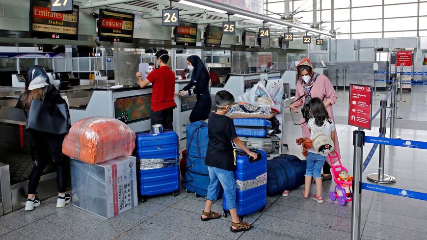 Outbound passengers arrive with their luggage at the Emirates check-in counter at the Iranian capital Tehran's Imam Khomeini International Airport, on July 17, 2020.