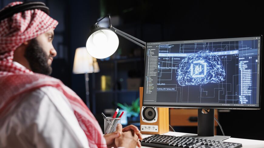Detailed image of Middle Eastern developer in front of desktop pc monitoring a complex network, ensuring data security and efficient computing using cloud, AI and machine learning.