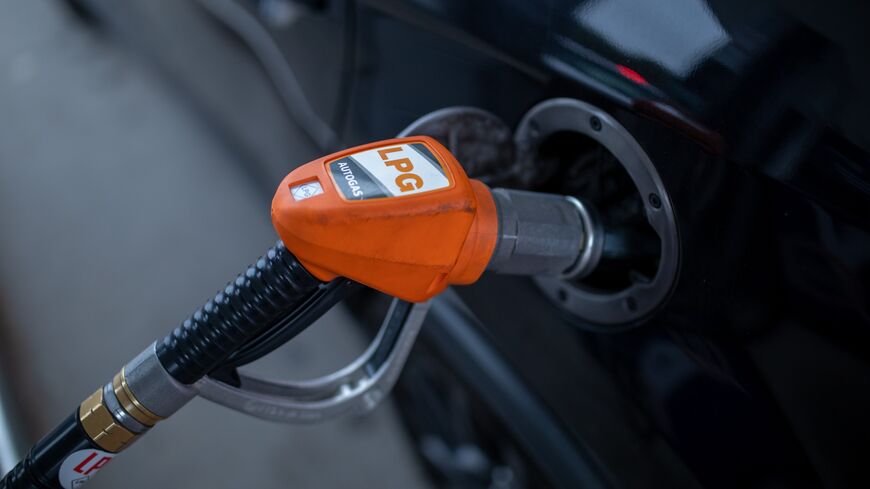 Close-up of an LPG dispenser nozzle filling a car's fuel tank. This illustrates the use of alternative fuel sources for automobiles. LPG is a cleaner-burning fuel compared to gasoline.
