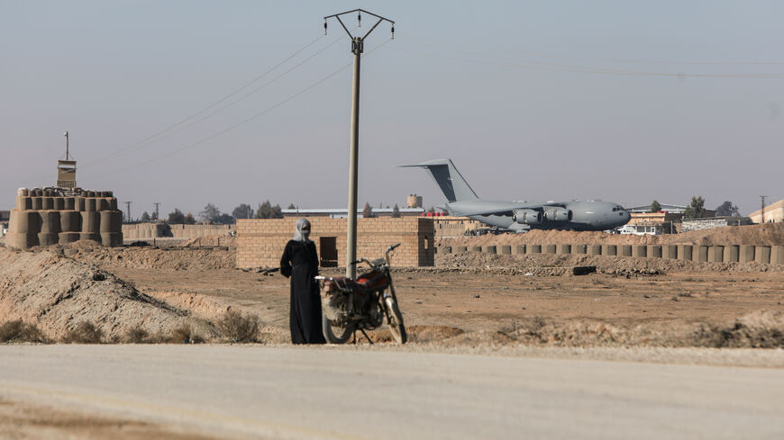 A person with a motorbike stands on the side of a road as US-led coalition plane operates at a base on Jan. 26, 2026 in Al-Shaddadi, Syria. 