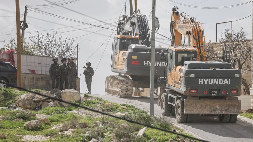 Excavators move along a street as Israeli forces are deployed during the demolition of the home of Palestinian Tariq al-Masalmeh in the village of Beit Awa, southwest of Hebron in the occupied West Bank, on Feb. 11, 2026. 