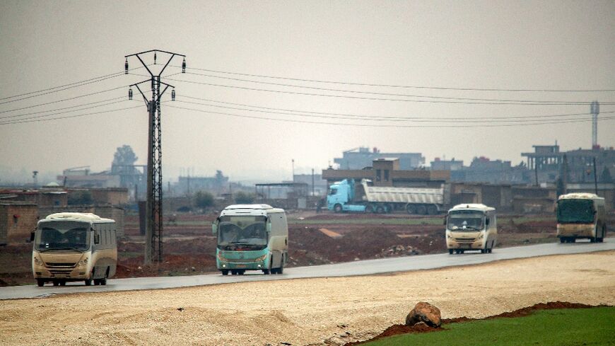 Buses in a US military convoy transporting Islamic State group detainees being transferred to Iraq from Syria