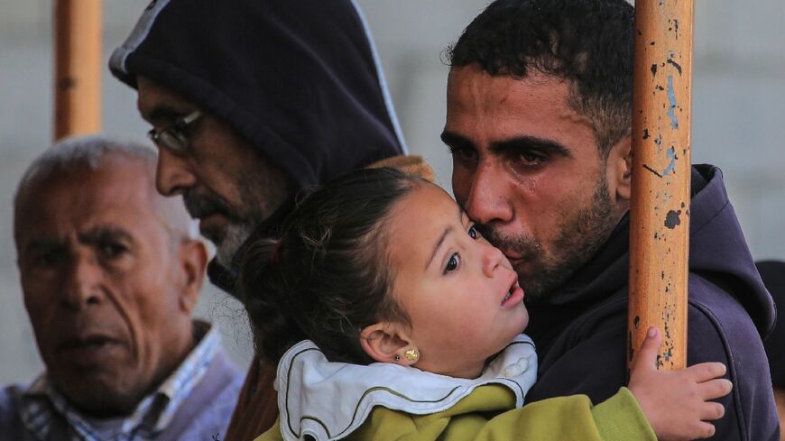 A mourner at Nasser Hospital in Khan Yunis kisses his baby daughter during the funeral of Palestinians killed in the strikes