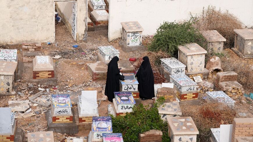 Iraqi Shia women visit a grave at Wadi al-Salam Cemetery in Iraq's holy city of Najaf as the war rages