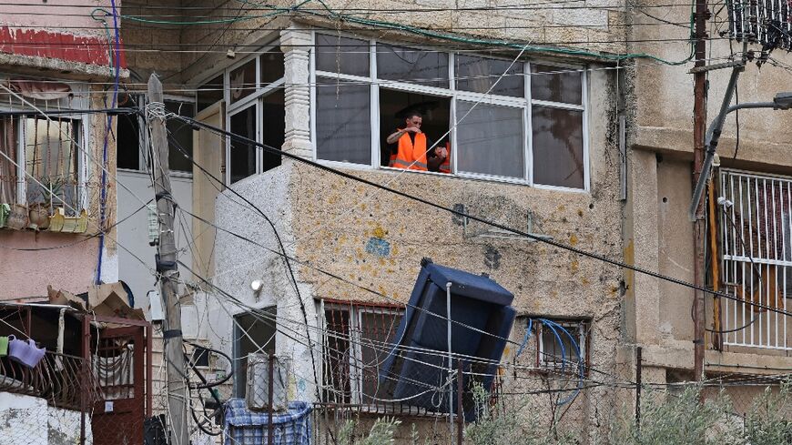 An Israeli authority employee throws a sofa from the window of a Palestinian home during the evictions