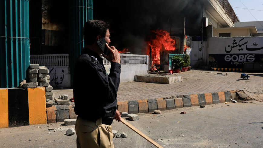 A police officer walks next to a checkpost set ablaze in a protest outside the U.S. Consulate General, following news of U.S. and Israeli strikes on Iran that killed supreme leader Ayatollah Ali Khamenei, in Karachi, Pakistan March 1, 2026. REUTERS/Akhtar Soomro