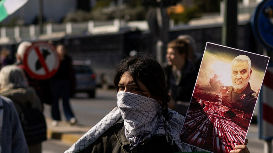 A protester holds an Iranian flag and a portrait of former Iranian military commander Qassem Soleimani during an anti-war demonstration outside the U.S. Embassy following strikes on Iran, in Athens, Greece, March 1, 2026. REUTERS/Stelios Misinas