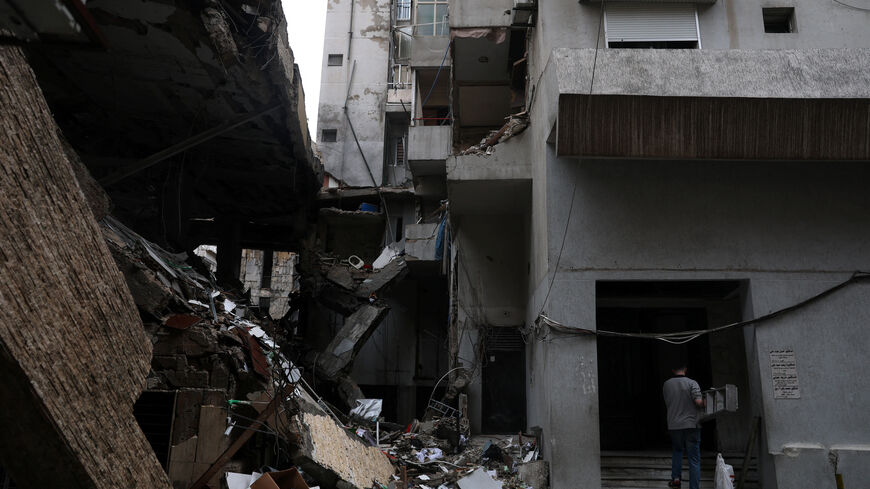 A man carries a ladder next to a damaged building in the aftermath of an Israeli strike in central Beirut, targeting what Israel said is a Hezbollah-affiliated bank, following an escalation between Hezbollah and Israel amid the U.S.-Israeli conflict with Iran, in Beirut, Lebanon, March 15, 2026. REUTERS/Claudia Greco