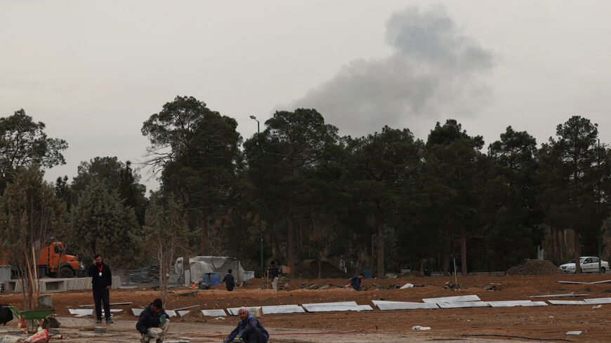 People work during an expansion of a cemetery, as smoke following airstrikes rises behind the Behesht-e Zahra cemetery, amid the U.S.-Israeli conflict with Iran, in Tehran, Iran, March 16, 2026. REUTERS/Alaa Al-Marjani