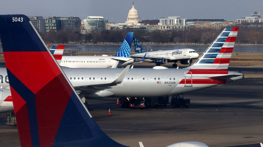FILE PHOTO: A JetBlue aircraft lands under the DC skyline featuring the U.S. Capitol building, near United Airlines, American Airlines and Delta Airlines aircraft on the tarmac at Ronald Reagan Washington National Airport in Arlington, Virginia, U.S. January 25, 2025.  REUTERS/Jim Urquhart/File Photo