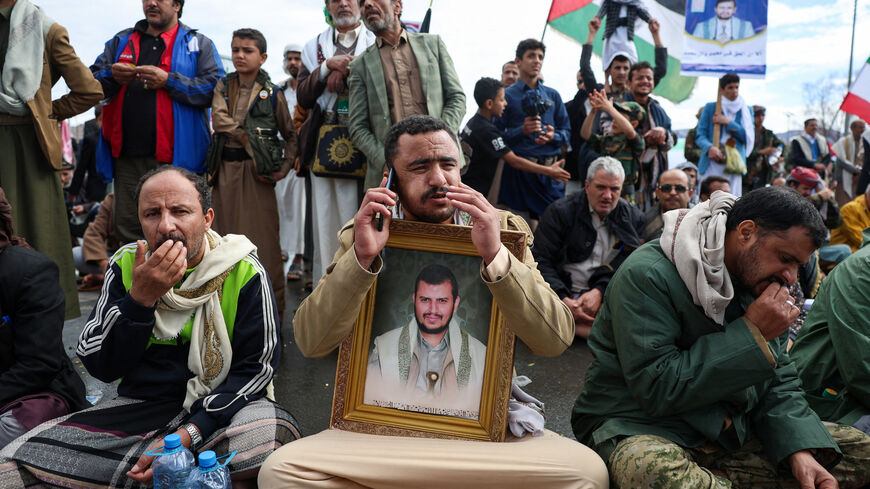 A Houthi supporter holds a poster with an image of the Houthis’s leader, Abdul-Malik al-Houthi, as he speaks on a mobile phone during a demonstration in solidarity with Iran, as the U.S.-Israeli conflict with Iran continues, in Sanaa, Yemen, March 27, 2026. REUTERS/Khaled Abdullah