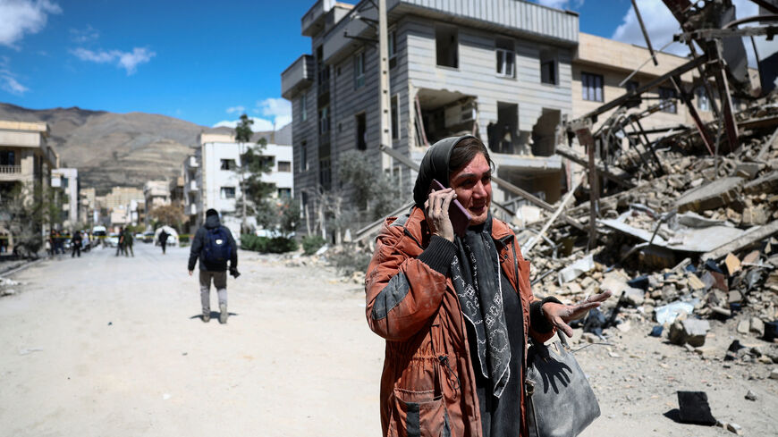 A woman talks on a phone while standing amid a damaged residential neighbourhood hit by a strike as the U.S.-Israeli conflict with Iran continues, in Tehran, Iran, March 30, 2026. Majid Asgaripour/WANA (West Asia News Agency) via REUTERS