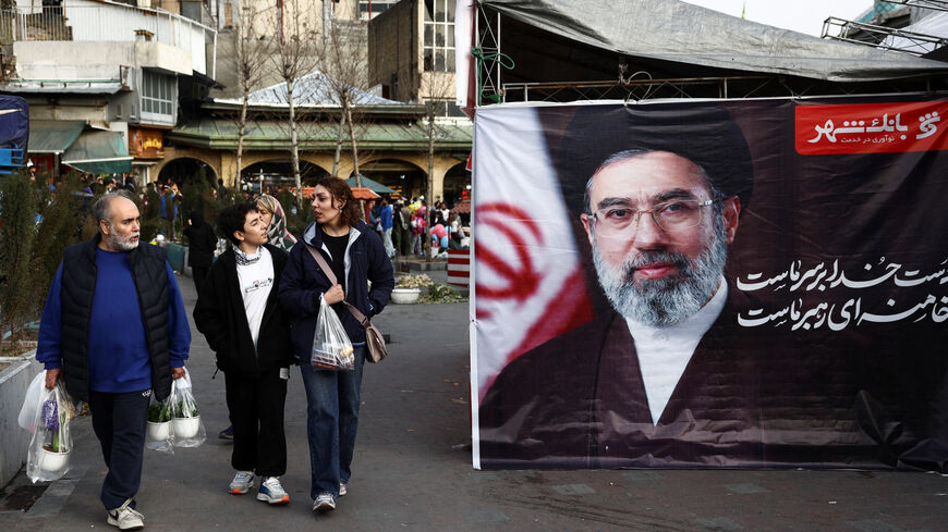 People walk next to a banner with a picture of Iran's new Supreme Leader, Mojtaba Khamenei, at Tajrish Bazaar, ahead of Nowruz, the Iranian New Year, amid the U.S.-Israeli conflict with Iran, in Tehran, Iran, March 19, 2026. Majid Asgaripour/WANA (West Asia News Agency) via REUTERS