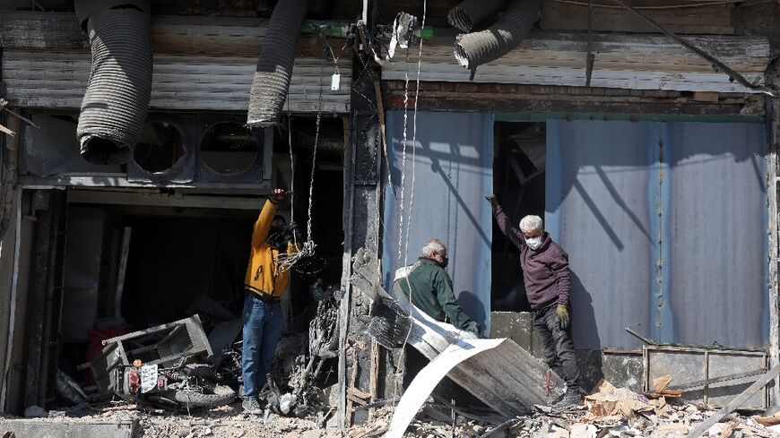 People inspect a damaged building following an airstrike in central Tehran 