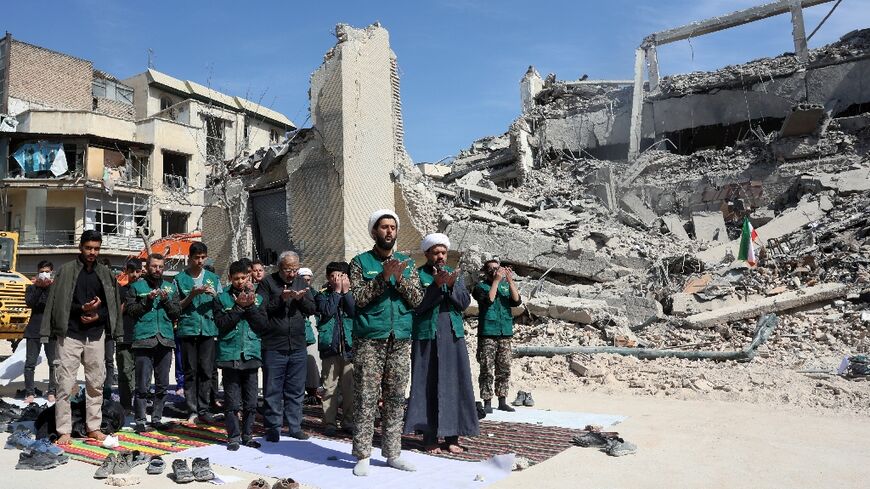 Iranian clerics and volunteers from the Bsij military who are helping clear the streets pray next to the rubble of a police station destroyed in airstrikes in central Tehran, on March 4, 2026.
