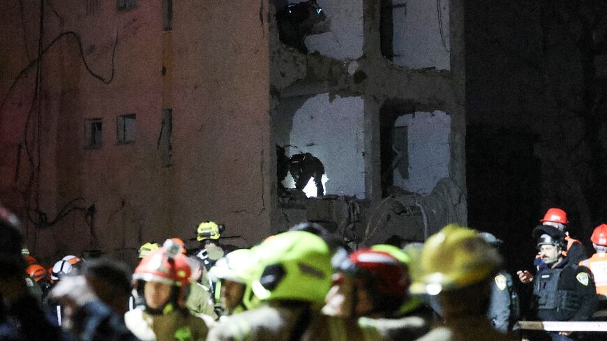 First responders inspect the site of an Iranian missile strike in Arad, Israel