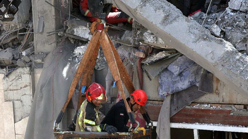 Firefighters try to recover the body of a victim in a damaged building in  southern Tehran