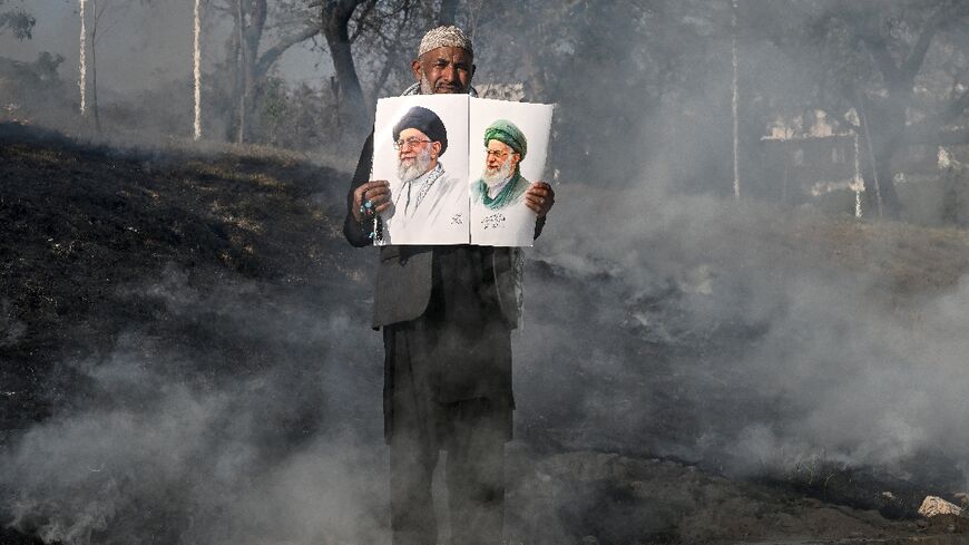 A man holds photos of Iran's late supreme leader Ayatollah Ali Khamenei as protesters attempt to storm the US embassy in Islamabad on March 1, 2026