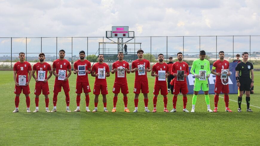 Iran players hold a photo of children said to have been killed in the Middle East war