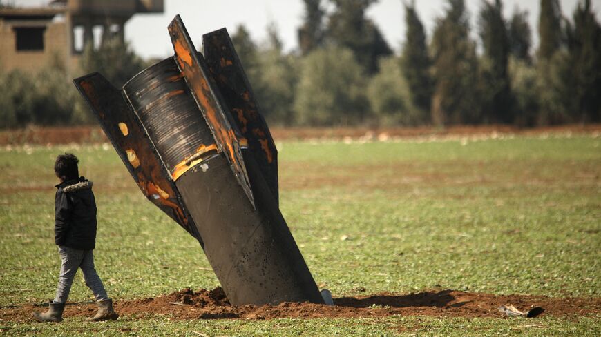 A boy walks past an unexploded missile that landed in an open field on the outskirts of Qamishli, eastern Syria, on March 5, 2026. 