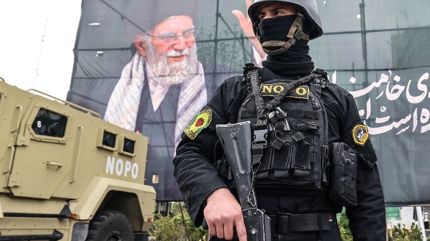 A member of the Iranian security forces stands guard next to a banner honouring Iran's slain supreme leader Ayatollah Ali Khamenei in Tehran 