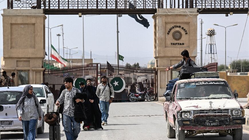 Pakistani nationals walk across the Taftan border after returning from Iran