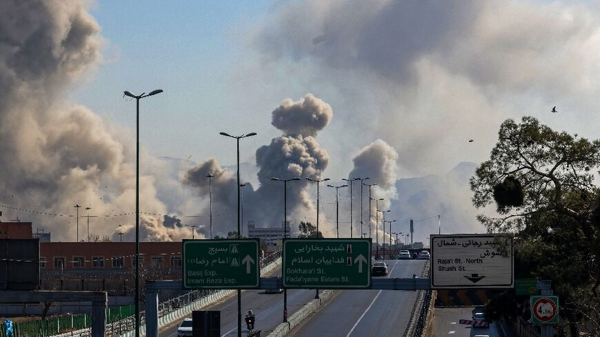 Motorists drive along an expressway as plumes of smoke rise after a strike in Tehran on March 5, 2026