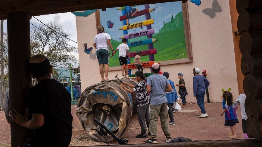 Children play with the remnant of an Iranian missile that fell in a school courtyard in the illegal Israeli settlement of Peduel, in the occupied West Bank