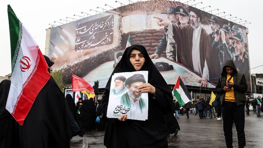A woman holds a picture of Iran's new supreme leader Ayatollah Mojtaba Khamenei as she takes part in a rally in Tehran on March 13, 2026