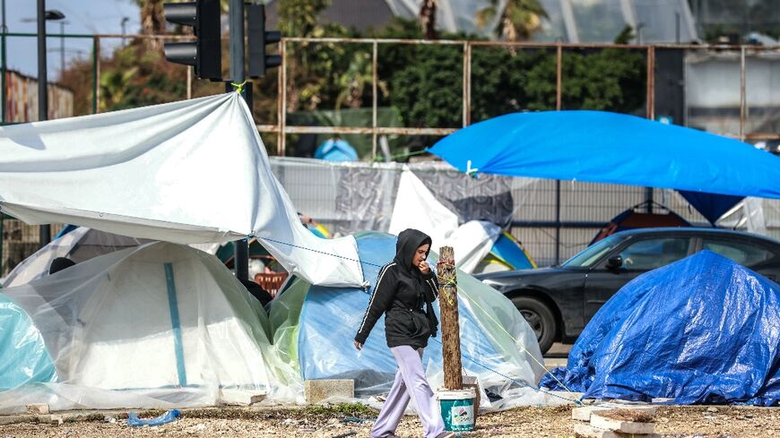 A displaced girl walks past tents covered in plastic sheeting to shield them from the stormy weather along Beirut’s seafront area