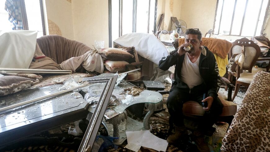 A man drinks tea inside his damaged house after returning to his hometown of Qana in southern Lebanon