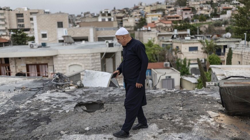 A member of the Druze community assesses the damage on a building hit overnight by a rocket fired from Lebanon, in the Israeli city of Shefa-Amr