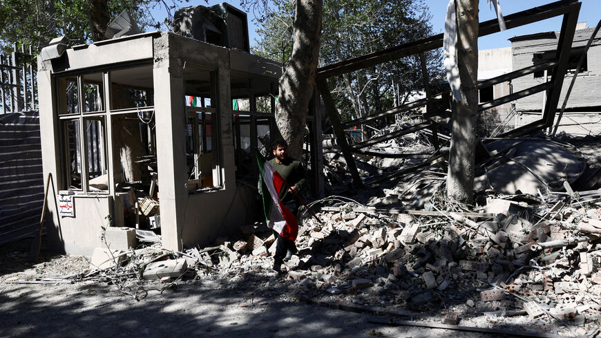 FILE PHOTO: A man carries an Iranian flag as he walks amidst the rubble of a building of the Sharif University of Technology, which was damaged in a strike, amid the U.S.-Israeli conflict with Iran, in Tehran, Iran, April 7, 2026. Majid Asgaripour/WANA (West Asia News Agency) via REUTERS /File Photo