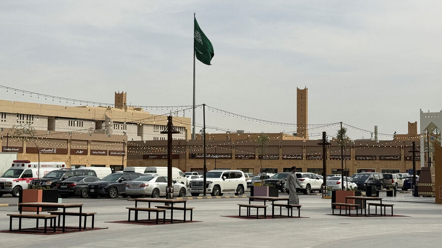 A man walks as a Saudi flag flutters in the background at Al Qaisareyah Market, amid the U.S.-Israeli conflict with Iran, in Riyadh, Saudi Arabia, March 4, 2026. Picture taken with a mobile phone. REUTERS/Ibraheem Abu Mustafa
